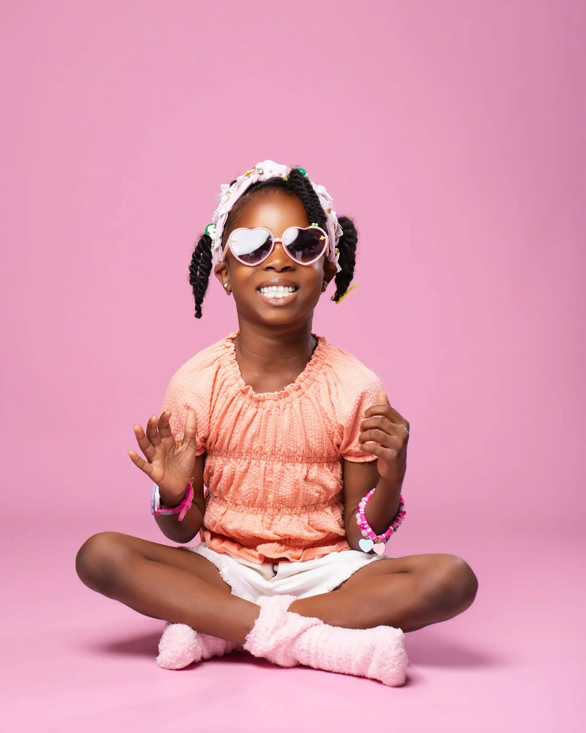Child wearing a heart necklace and pastel accessories