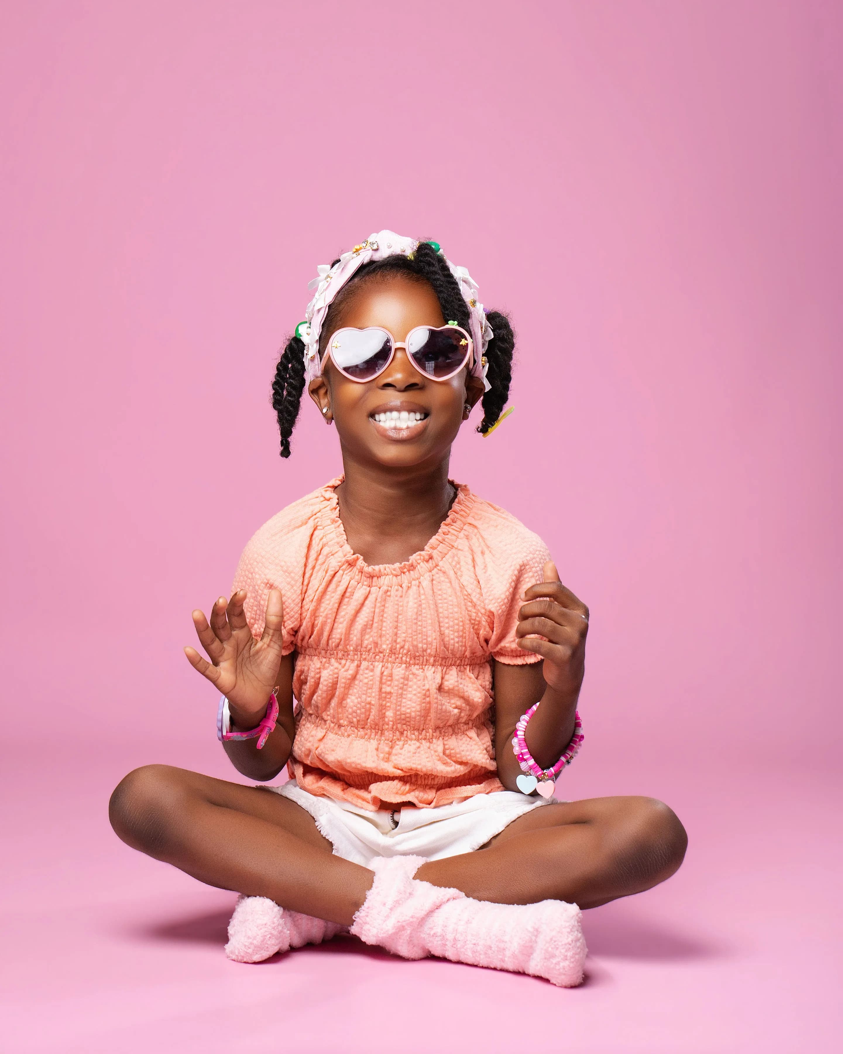 Child wearing a heart necklace and pastel accessories